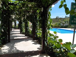 A covered walkway with a pool in the background. - Summer paradise, total relaxation on your vacation (Stgo)