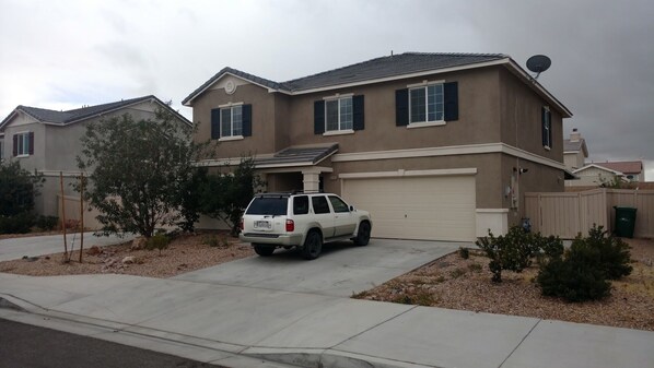 A two-story house with a garage, a driveway, and a parked SUV.