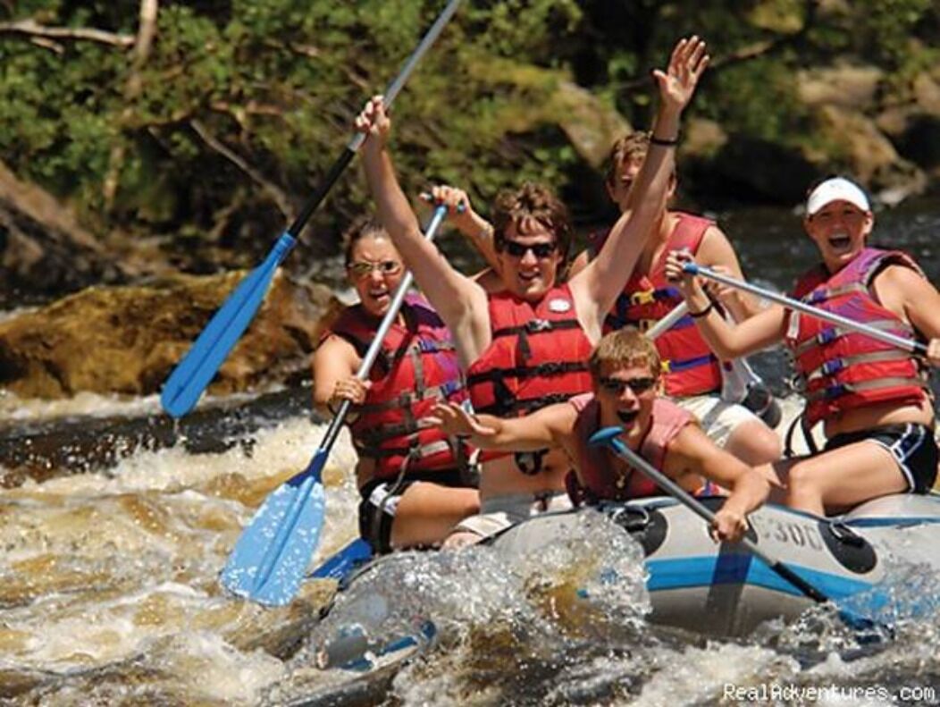 Een groep mensen peddelt in een raft over een rivier.