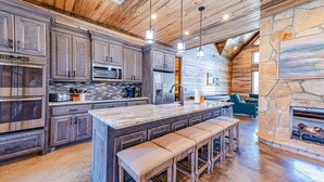 A spacious kitchen with wooden cabinets, stainless steel appliances, and a large island with bar stools.