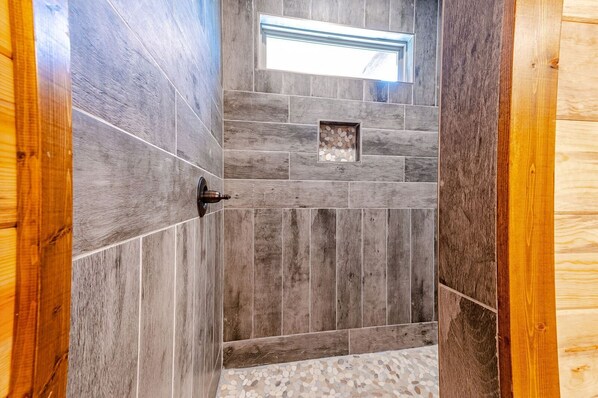 Una ducha con azulejos de piedra y una puerta de madera.