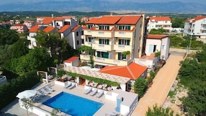 A hotel with a swimming pool, multiple balconies, and a view of the surrounding landscape. - Room in Novalja with Air condition, WIFI (3764-9) (Novalja)