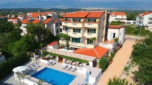 Et hotel med swimmingpool, flere balkoner og udsigt over det omkringliggende landskab.