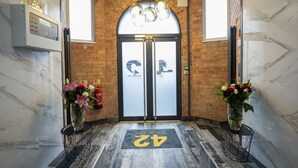 A hotel lobby with a marble floor, a black and white checkered doormat, and two vases with flowers. - 42 Apart-hotel (Scunthorpe)
