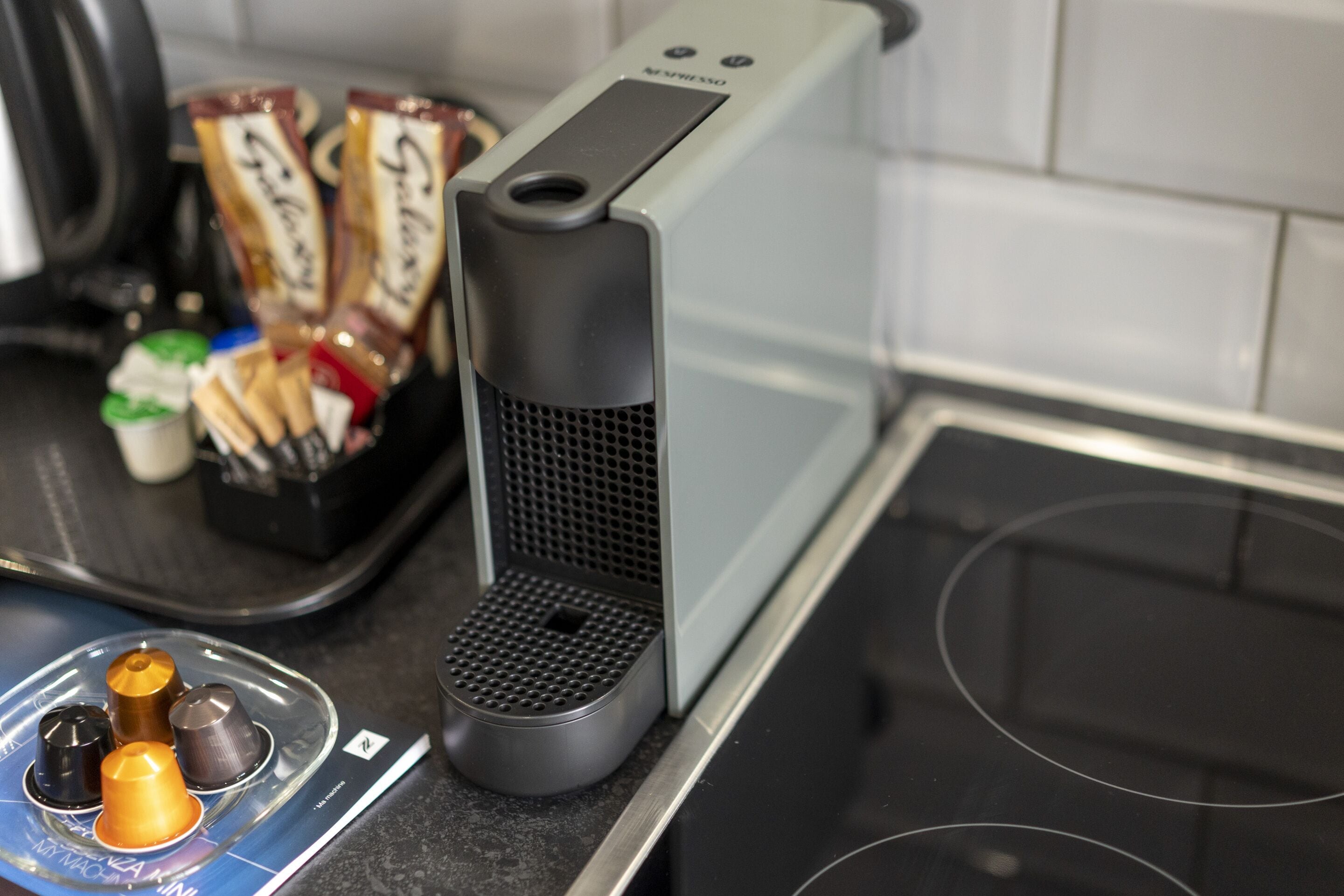 A kitchen with a coffee machine, a tray with snacks, and a booklet on the counter.
