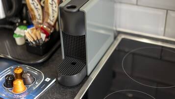 A kitchen with a coffee machine, a tray with snacks, and a booklet on the counter.