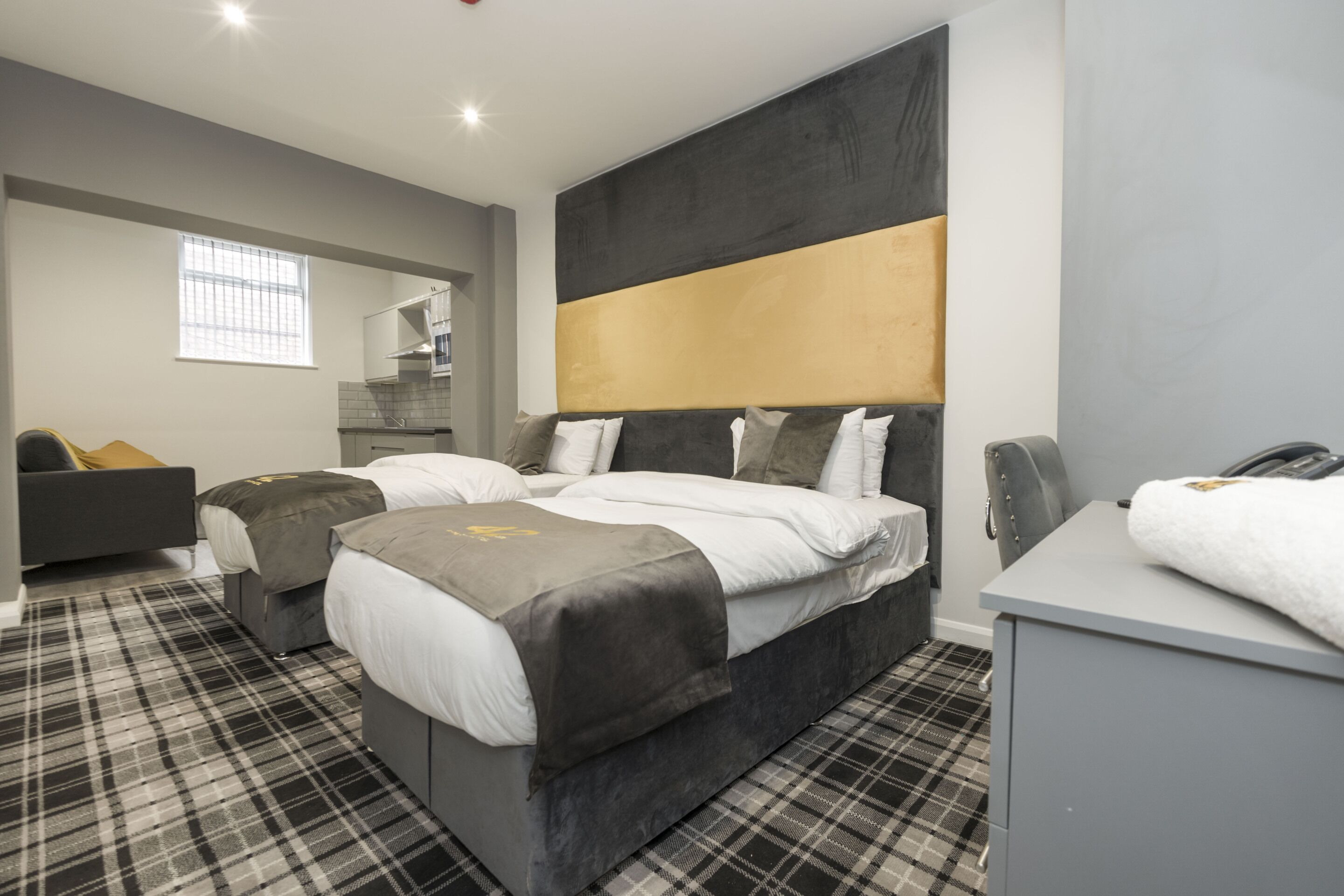 A modern hotel room with a large bed, a sofa, and a desk.