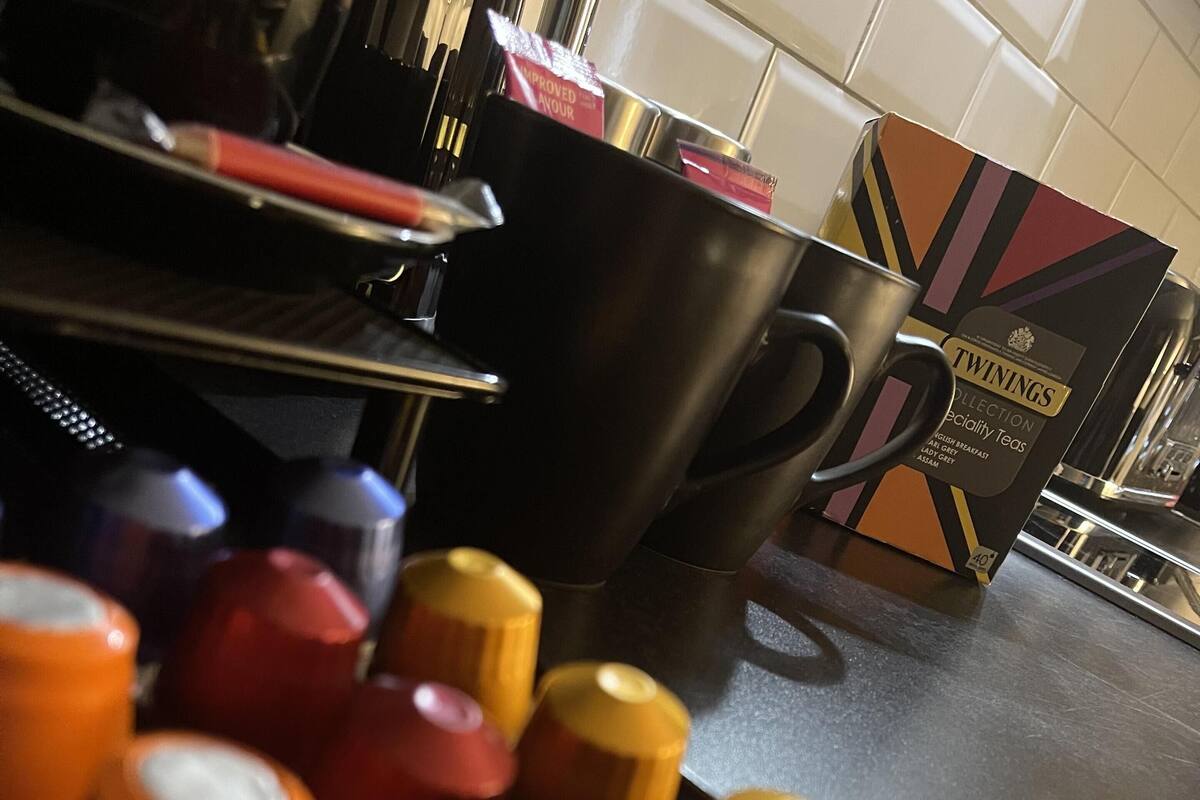 A kitchen counter with a coffee machine, a box of Twinings tea, and a container of spices.