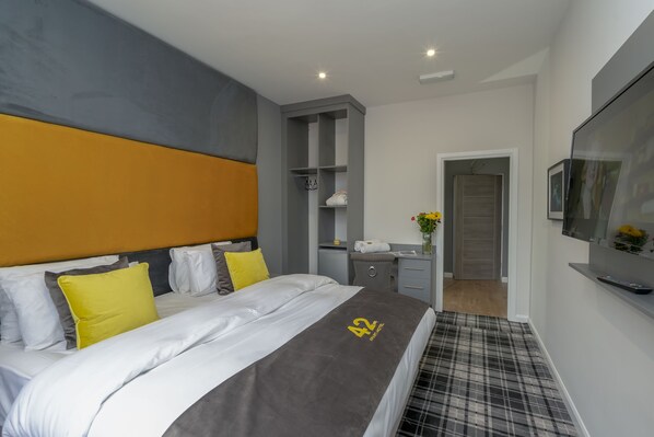 A modern hotel room with a large bed, a desk, a wardrobe, and a television. - 42 Apart-hotel (Scunthorpe)