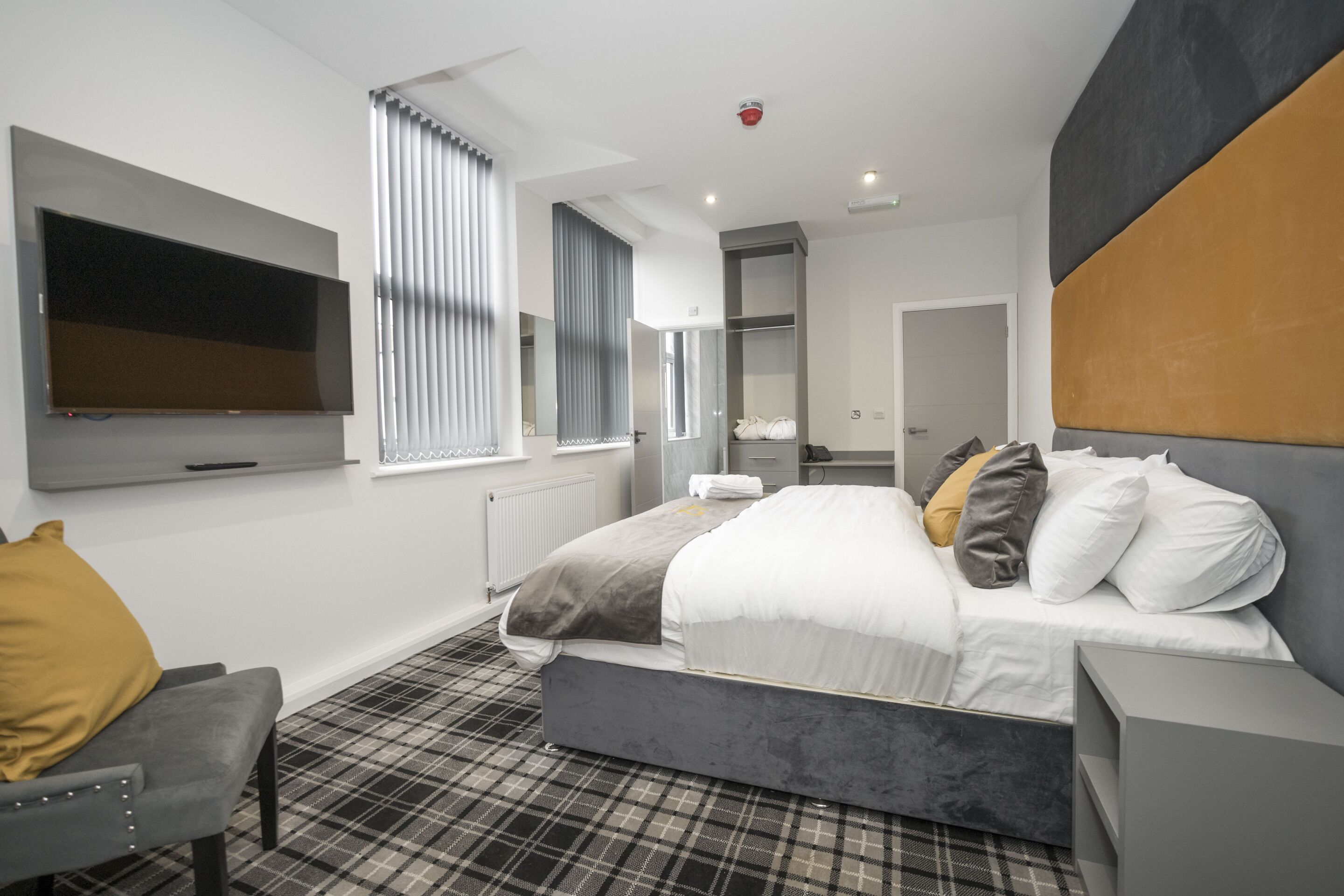 Une chambre à coucher moderne avec un lit, une télévision, une chaise et une armoire.