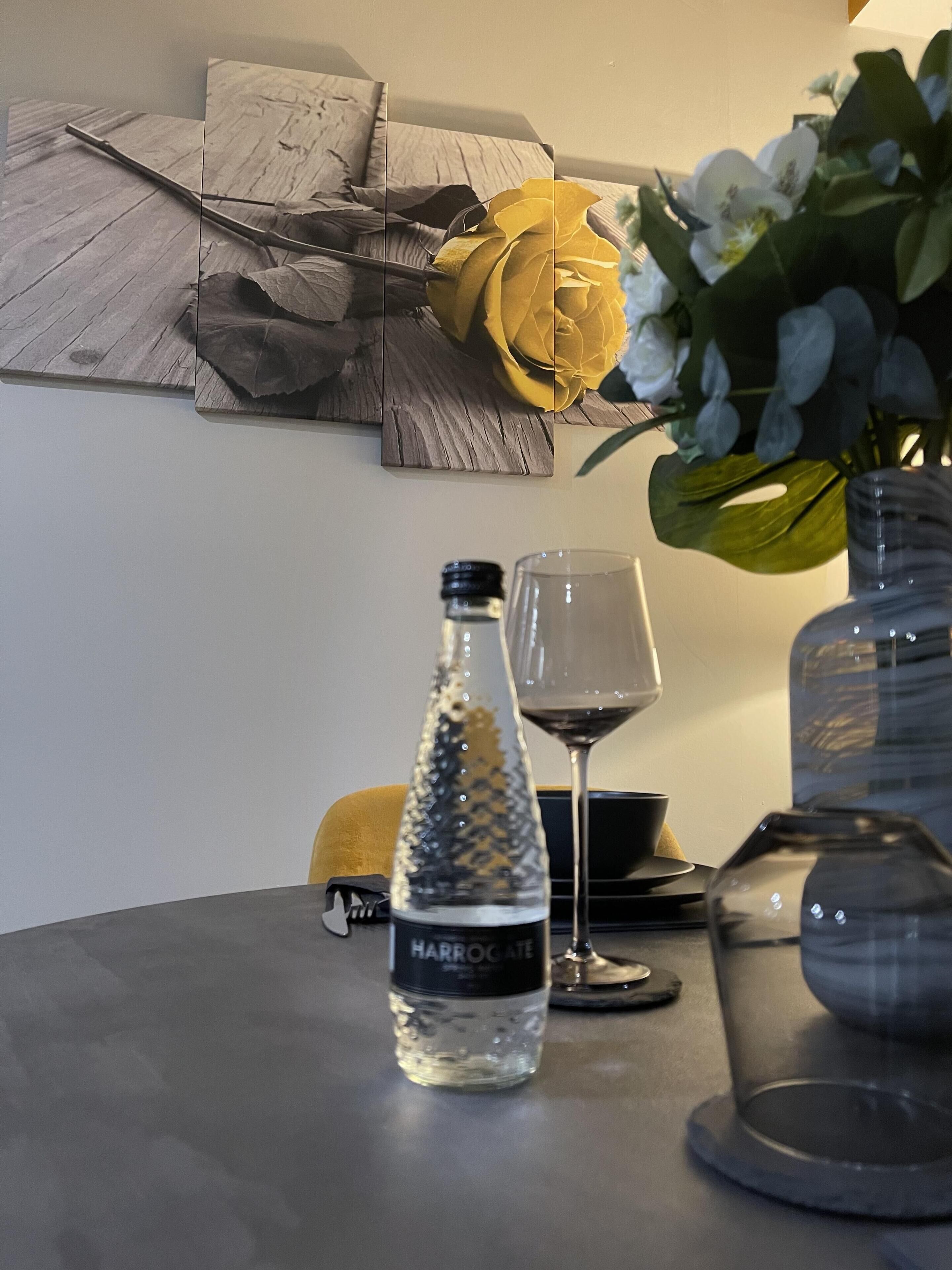 A table with a water bottle, a wine glass, and a vase with flowers.