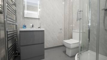 Een moderne badkamer met een douchecabine van glas, een wit toilet en een grijze wastafel met een spiegel erboven.