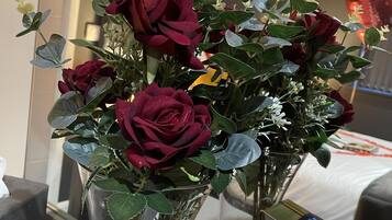 Un ramo de rosas rojas en un florero transparente sobre una mesa con una caja de galletas de chocolate al lado.