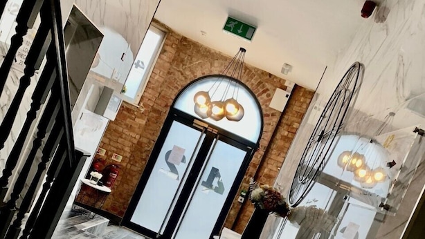 A modern hotel lobby with a marble floor, a staircase, and a reception area with a brick wall and a glass door. - 42 Apart-hotel (Scunthorpe)