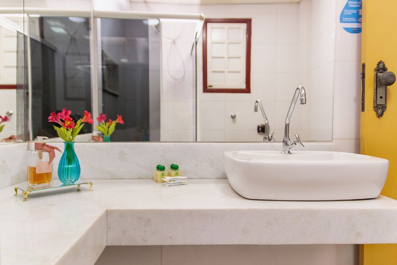 A bathroom with a white sink, two faucets, a mirror, and a shower area.