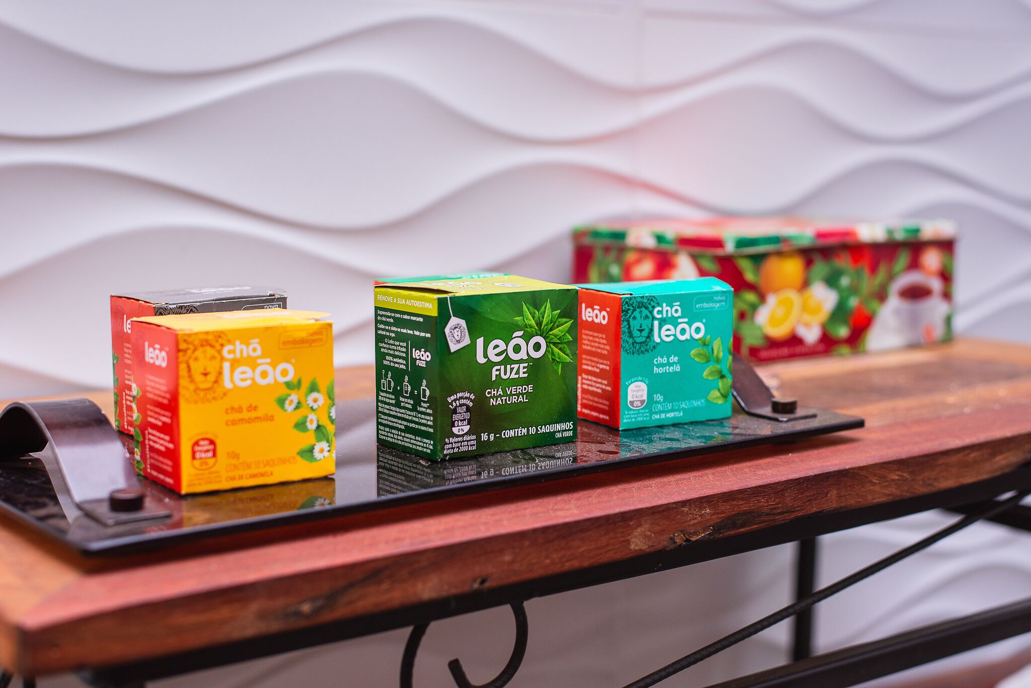 A display of tea boxes on a wooden table with a wavy white background.