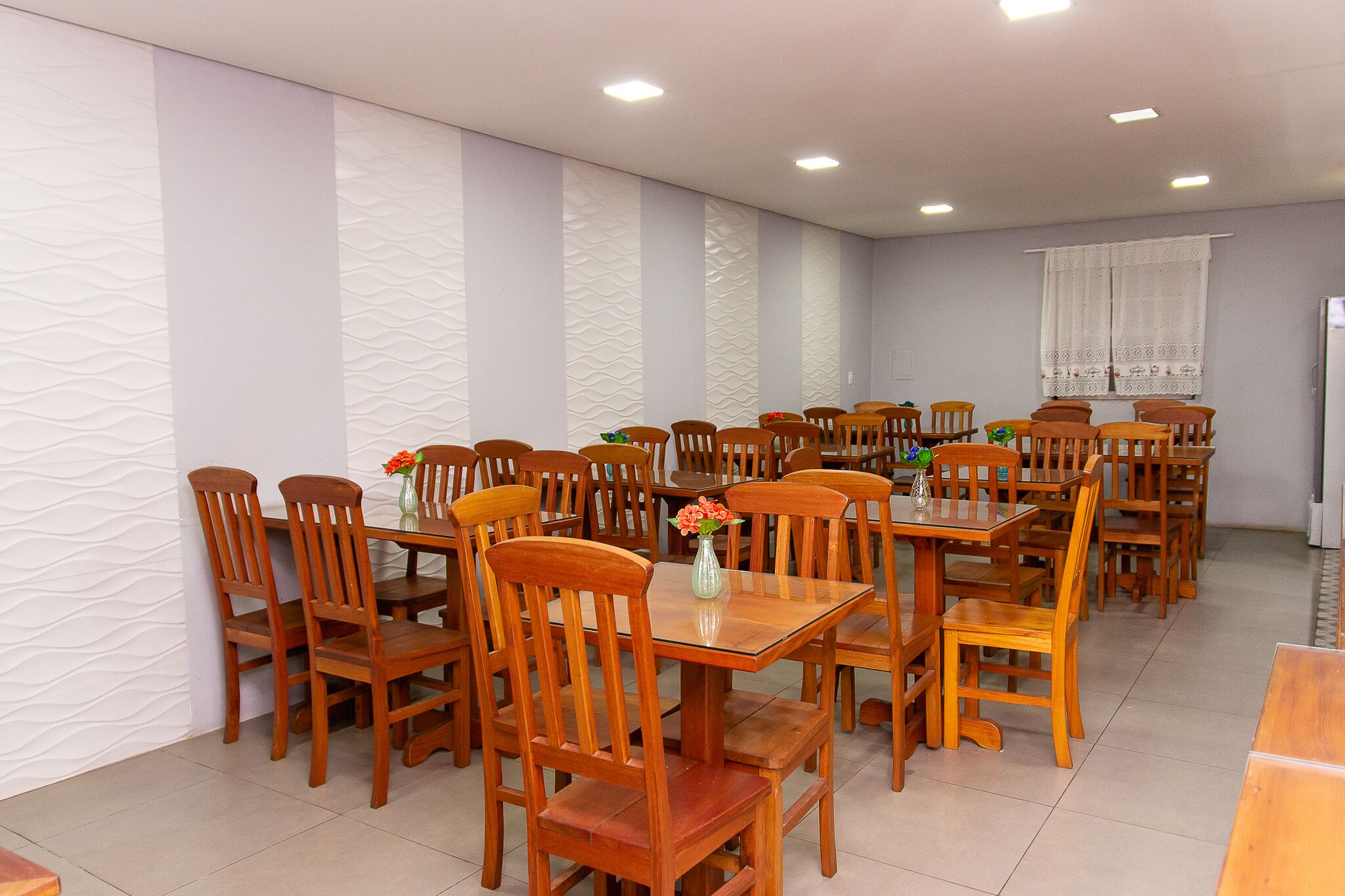 A dining area with multiple wooden tables and chairs, arranged in rows.