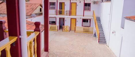 A building with a tiled roof, a staircase, and a balcony with yellow railings.