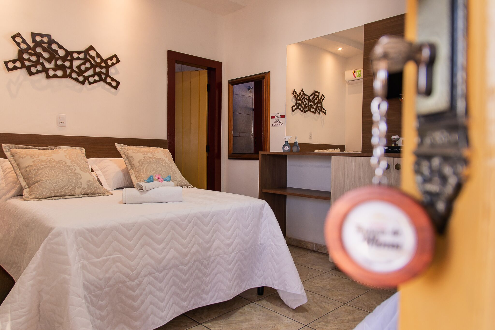 A hotel room with a bed, a bathroom mirror, and a wall-mounted decorative piece.