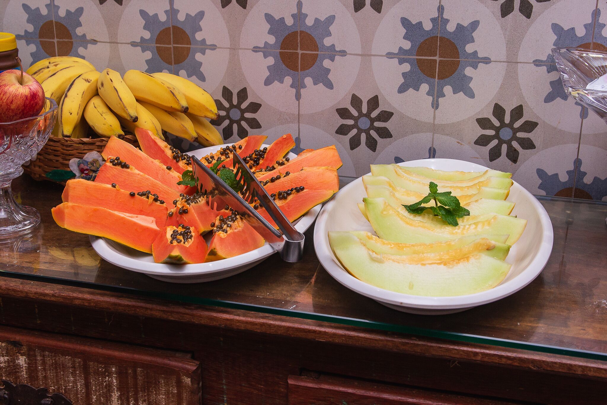 A fruit platter with sliced papaya, cantaloupe, and bananas on a table.