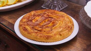 Un pastel redondo con corteza dorada sobre un plato blanco.