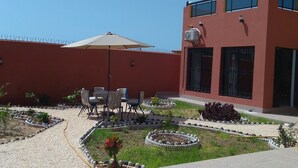 Un patio con zona de estar, un edificio con ventanas protegidas y cielo despejado.