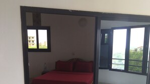 Un dormitorio con cama, ventana y vista a follaje.