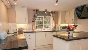 A modern kitchen with white cabinets, a black countertop, and a window with curtains. - Fisher Granary (Lampeter)
