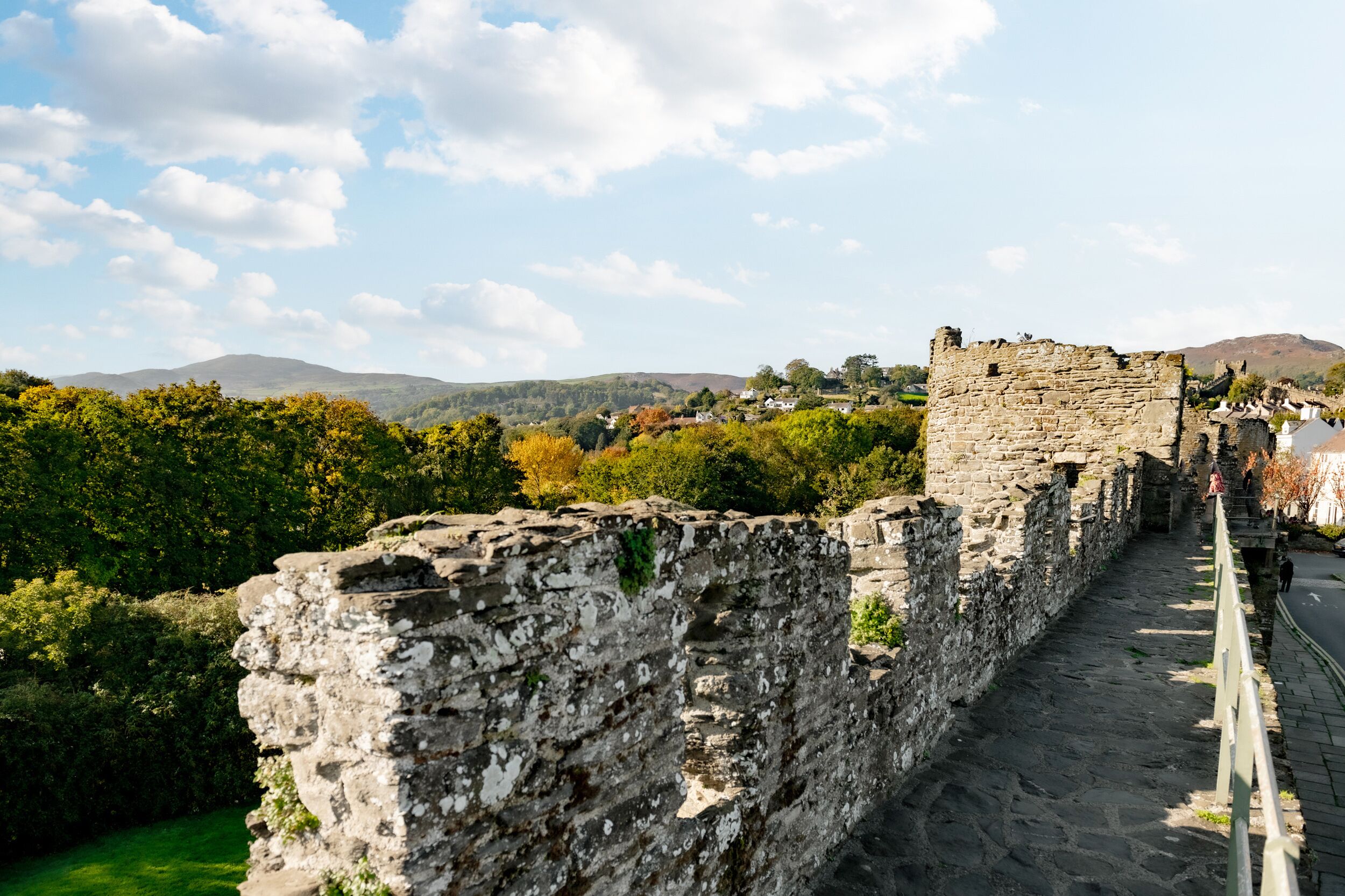 Un mur de pierre avec un sentier menant aux ruines d’un château.