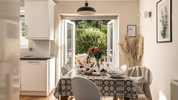 Un comedor con una mesa dispuesta para cuatro personas, un armario blanco y vistas al exterior.