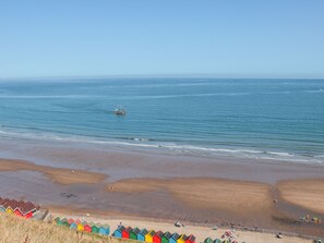 Une plage avec des cabanes colorées et un bateau sur l’eau.