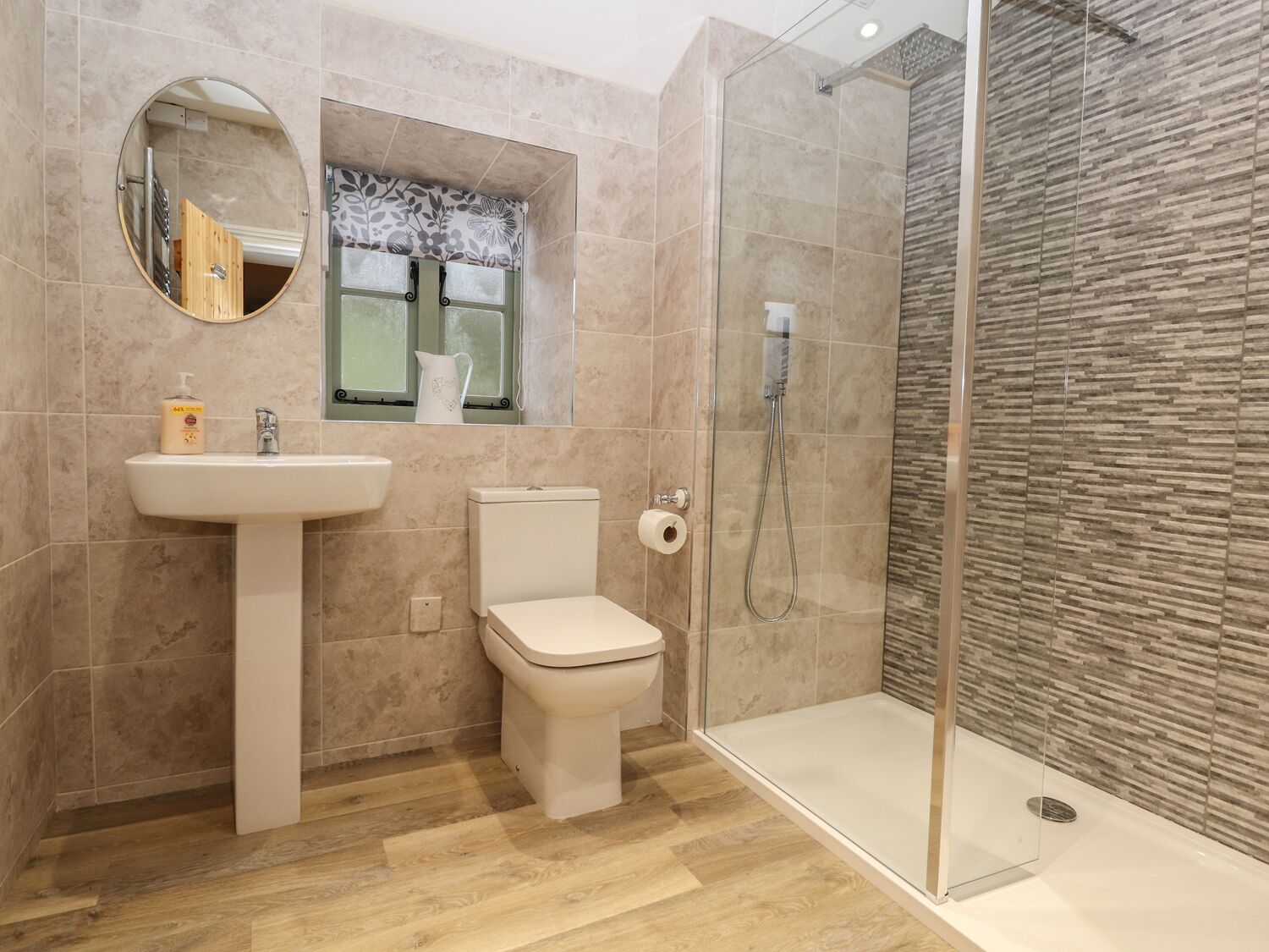 Een moderne badkamer met een wastafel, toilet en een douchecabine met glazen wanden.