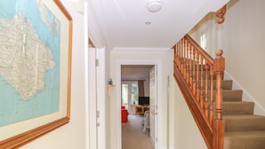 A hallway with a wooden staircase, a map on the wall, and a door leading to another room. - Hurst View (Freshwater)