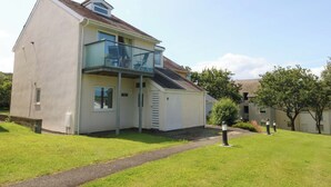 A two-story house with a balcony, a paved driveway, and a well-maintained lawn. - Machlud Ynys (Y Felinheli)