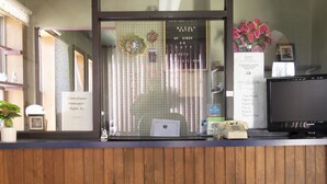 A reception desk with a wooden panel backdrop, a computer, a telephone, and a framed welcome sign. - OYO Hotel Wilkes-Barre East (Wilkes-Barre)