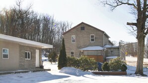 A two-story house with a stone facade, a front porch, and a snow-covered yard. - OYO Hotel Wilkes-Barre East (Wilkes-Barre)