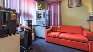 A compact living space with a kitchenette, a red sofa, and a television. - OYO Hotel Wilkes-Barre East (Wilkes-Barre)