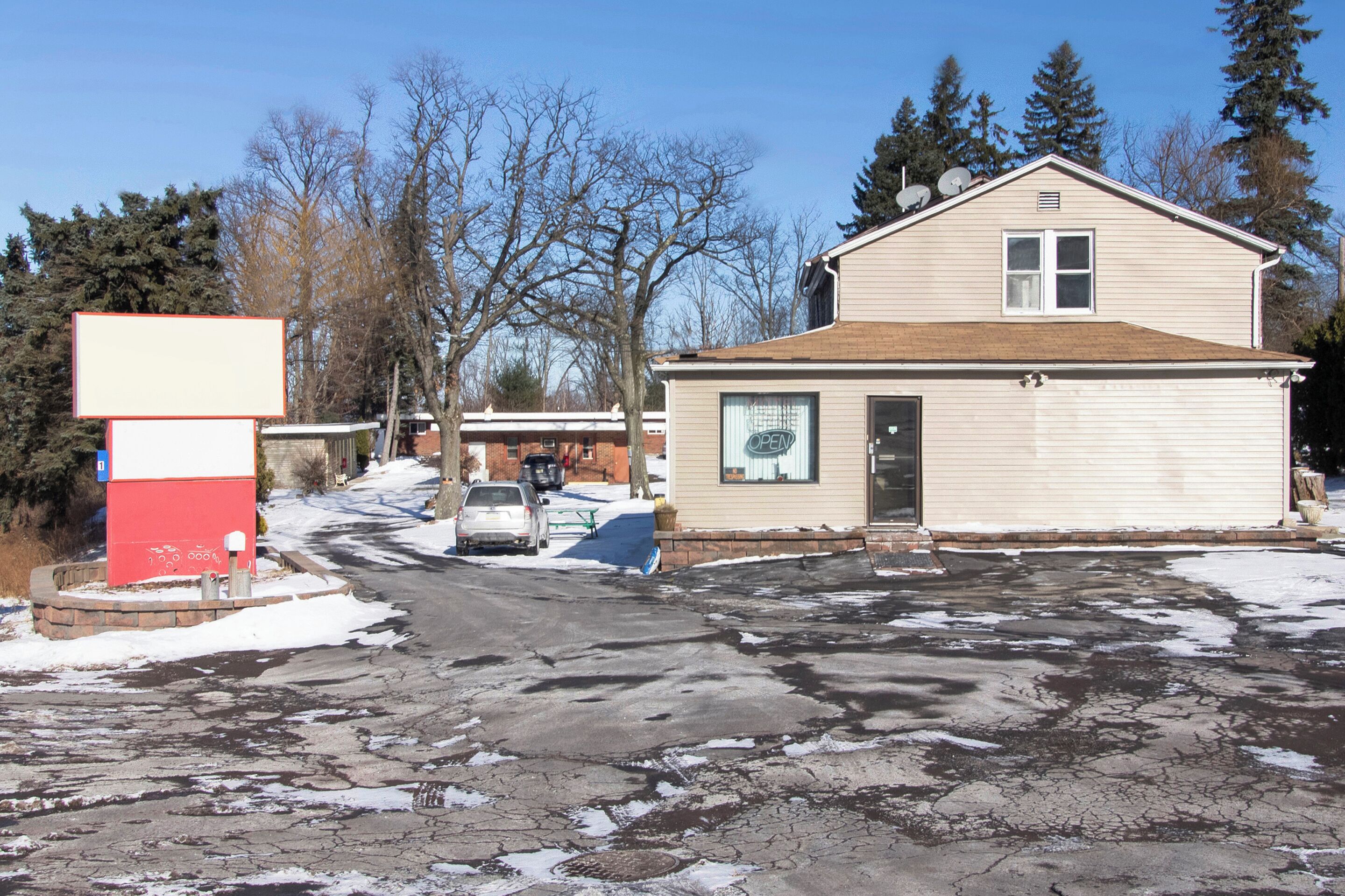 Un bâtiment à deux étages avec un garage, une allée et un terrain recouvert de neige.