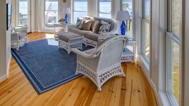 A spacious living room with a large window, a ceiling fan, and a blue patterned rug. - Great house with dock on Lake Murray SC.  Excellent for families, fishing, fun (Prosperity)