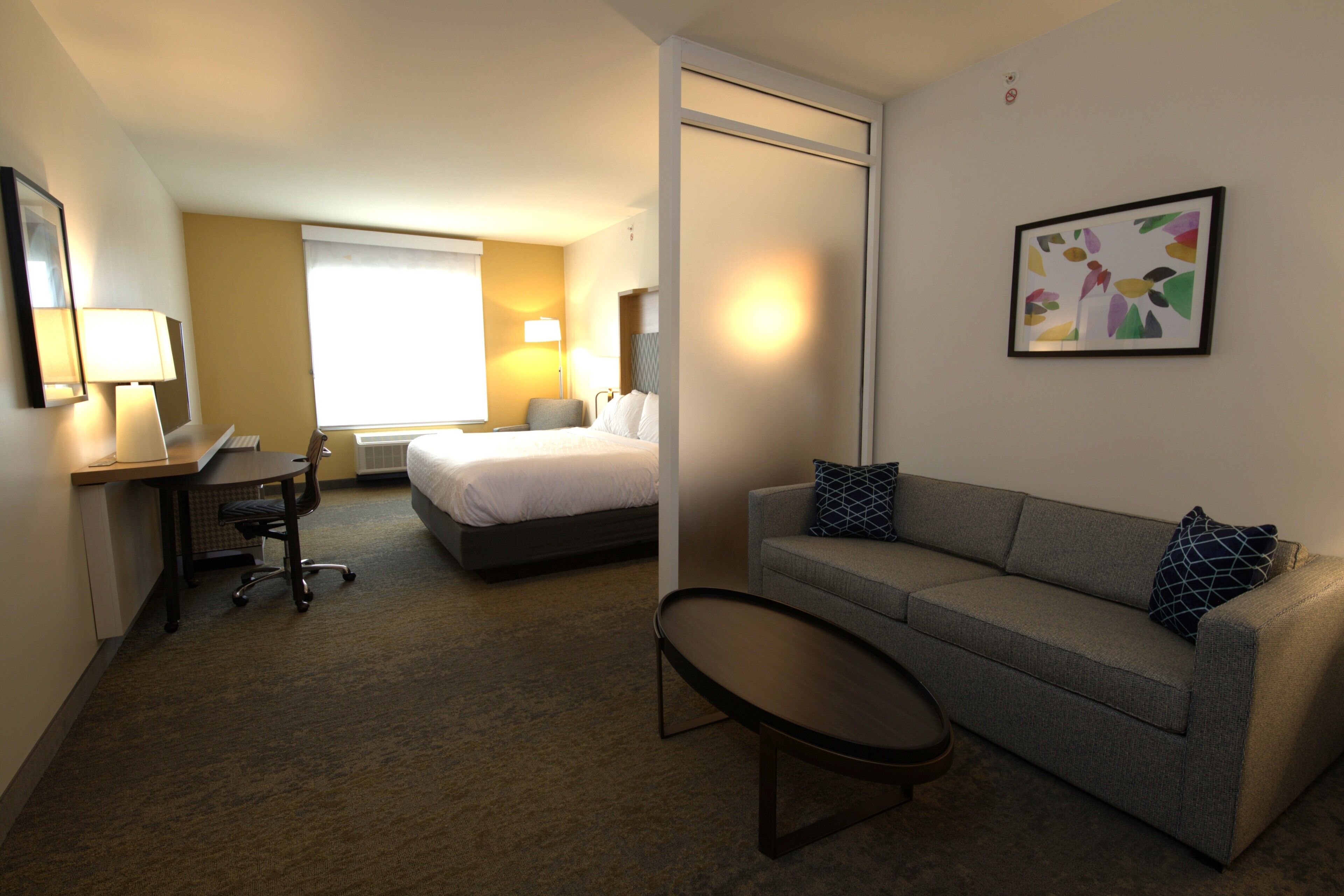 Una habitación de hotel con cama, sofá, escritorio y una silla.