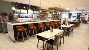 A modern bar area with a counter, stools, and a seating area with tables and chairs. - Holiday Inn Hotel & Suites Hopkinsville - Convention Ctr by IHG (Hopkinsville)