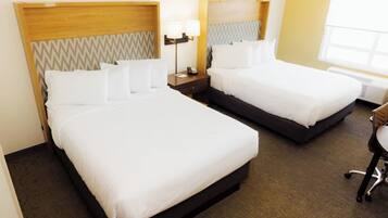 Two single beds with wooden headboards, a bedside table with a lamp, and a chair.