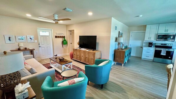 A living room with a sofa, armchairs, a television, and a wooden cabinet.
