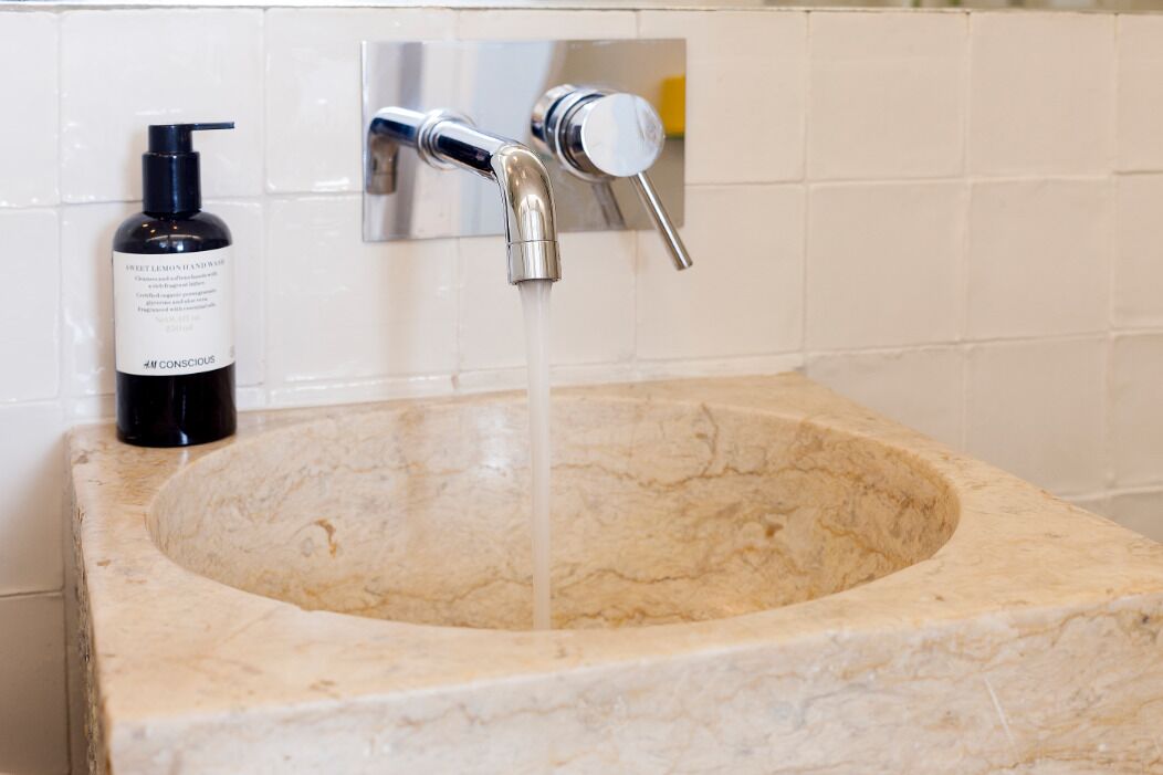 A bathroom with a marble sink, a bottle of hand soap, and a faucet.