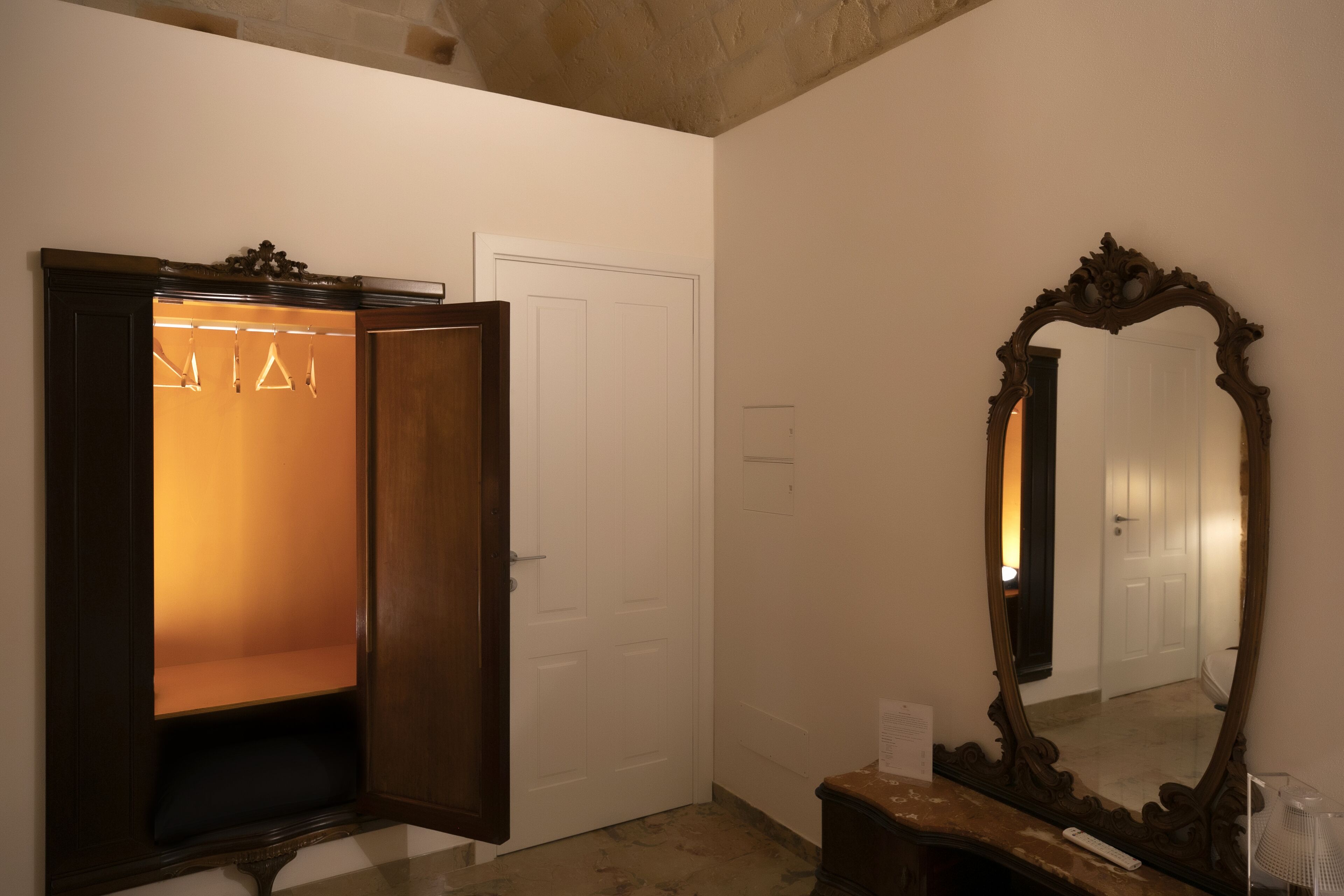 A room with a wooden wardrobe, a mirror, and a door.