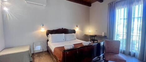 Un dormitorio con cama de madera, mesitas de noche, una silla y una ventana con cortinas.