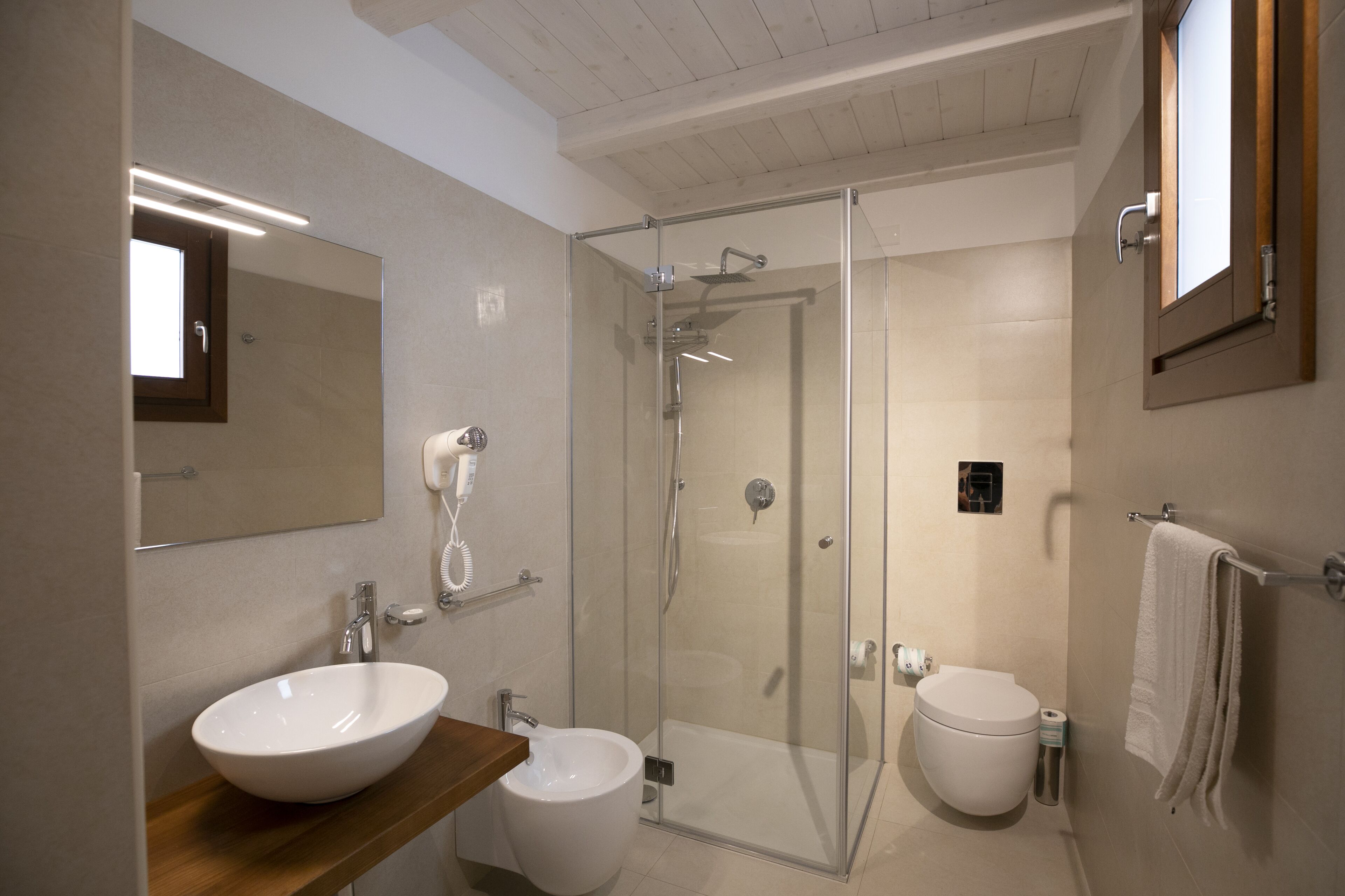 A modern bathroom with a glass-enclosed shower, two sinks, and a large mirror.