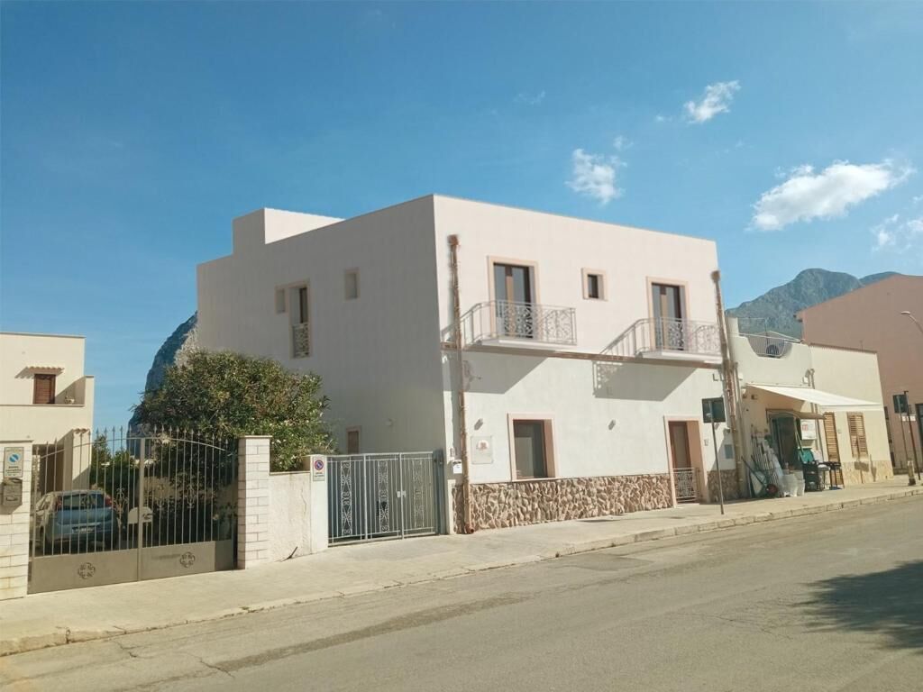 A two-story building with a balcony, a stone base, and a clear sky.