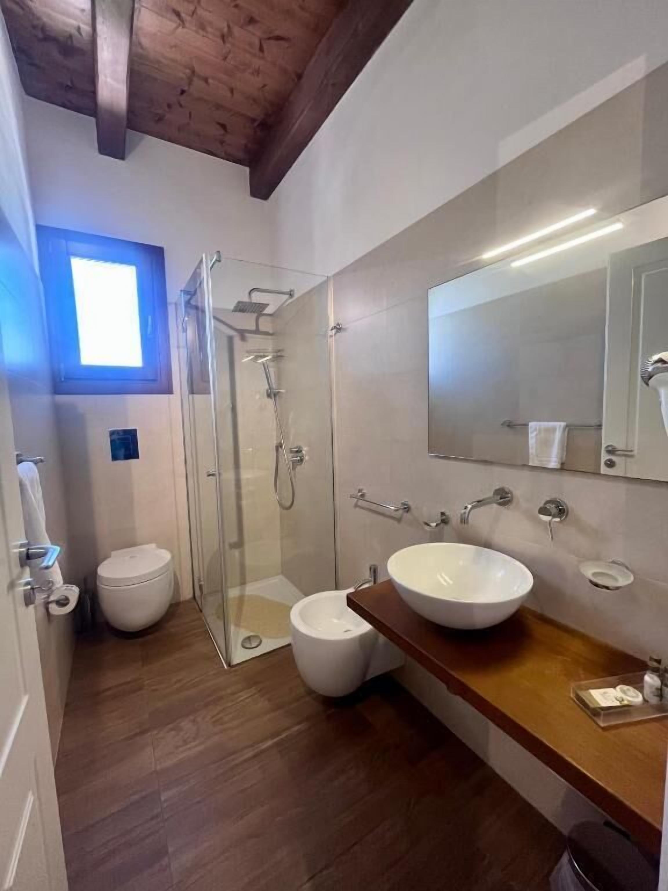 Un baño moderno con cabina de ducha de vidrio, un lavamanos grande y un inodoro.