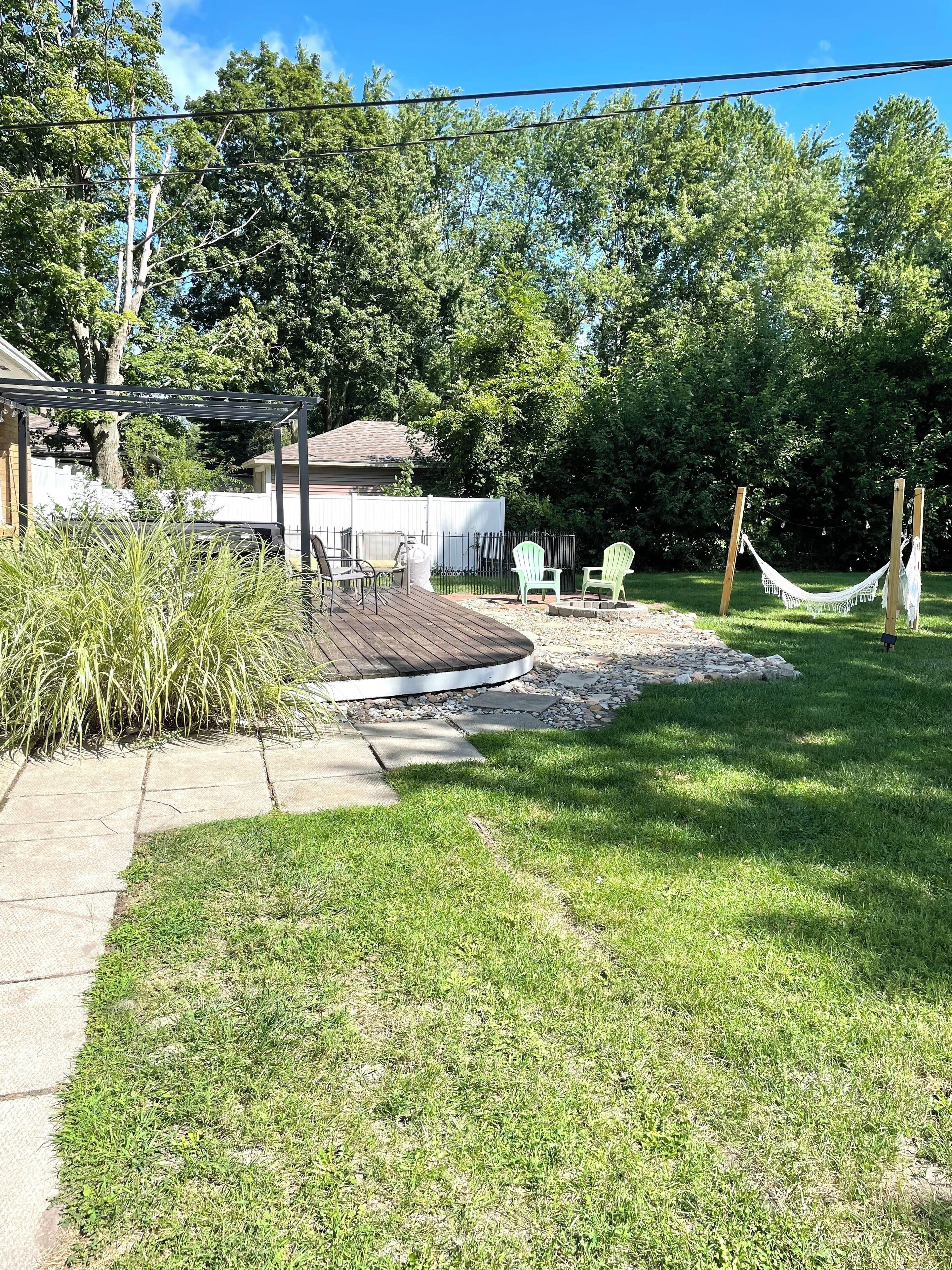 A backyard with a wooden deck, outdoor seating, and a hammock.